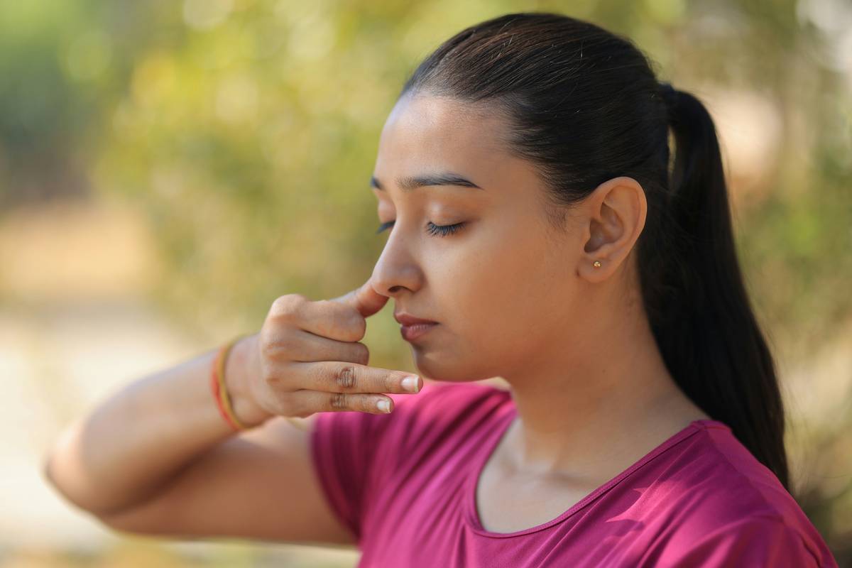 Woman practicing lung vitality technique with hands on diaphragm, seated calmly outdoors